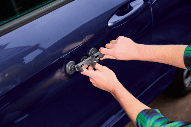 Person using a dent puller on a car door.