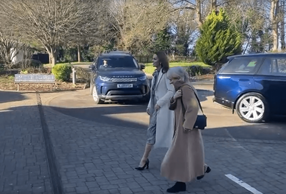 Two women walking near parked cars.