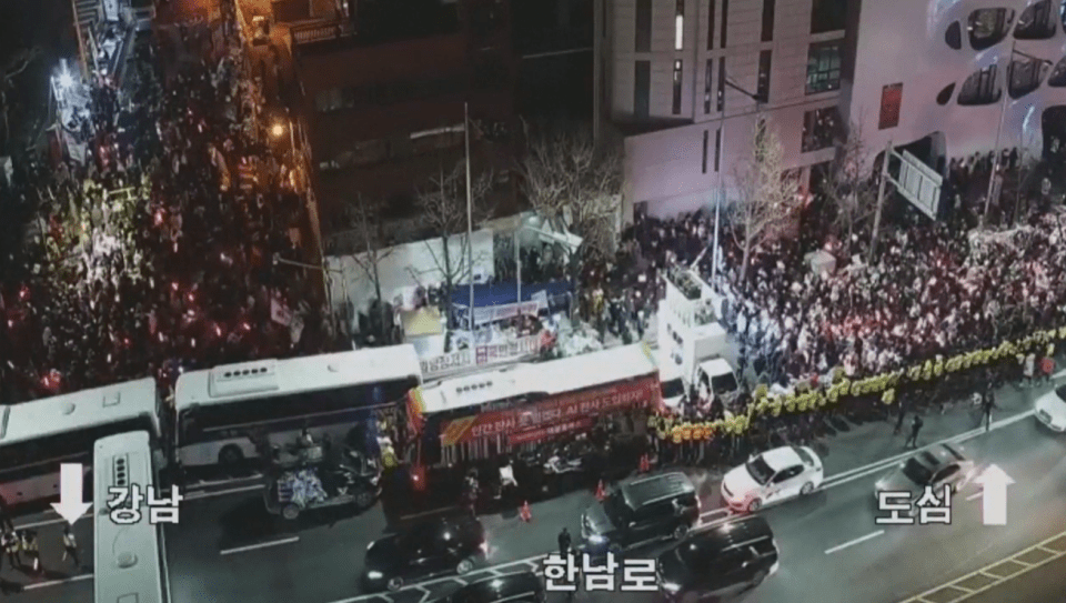 Aerial view of a large crowd gathered in a city street at night.