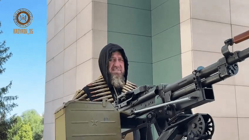 Man with ammunition vest and large machine gun.