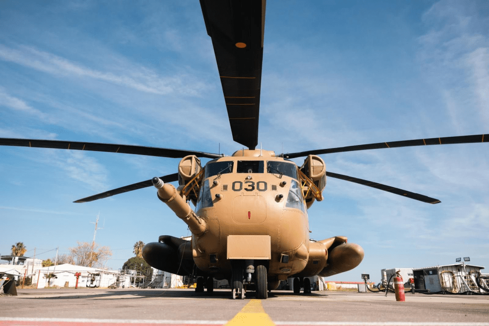 Tan military helicopter on tarmac.