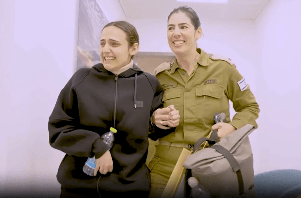 A woman in civilian clothes cries while holding hands with a smiling soldier.