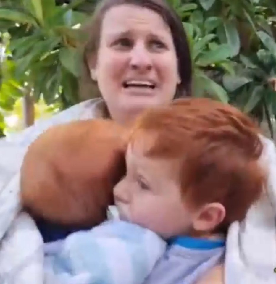 Woman holding two young children.