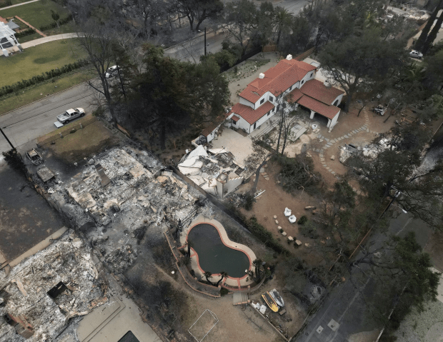 Aerial view of a house that survived a fire, next to a fire-damaged house.