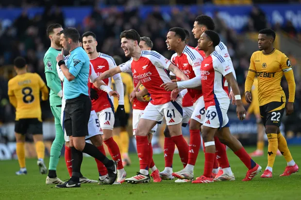 Arsenal players arguing with a referee.