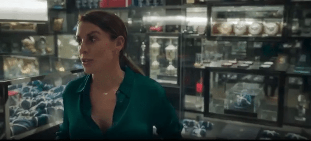 Woman in green shirt looking concerned in a trophy room.