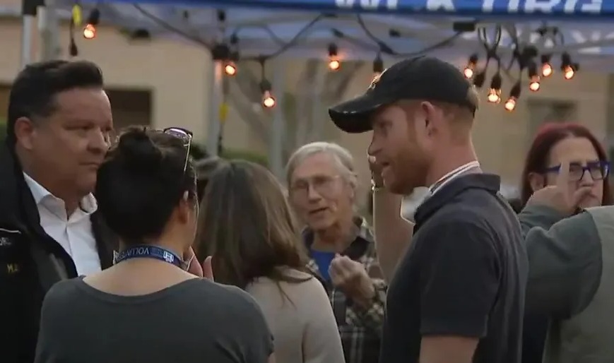 Prince Harry speaking with people at an outdoor event.