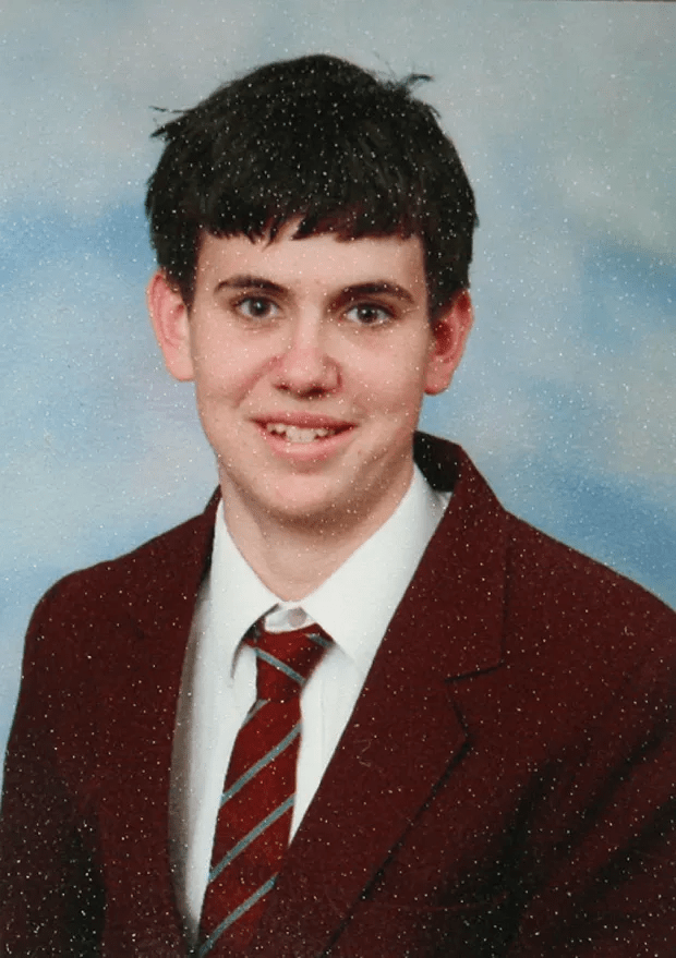 Portrait of a young man in a maroon blazer and striped tie.