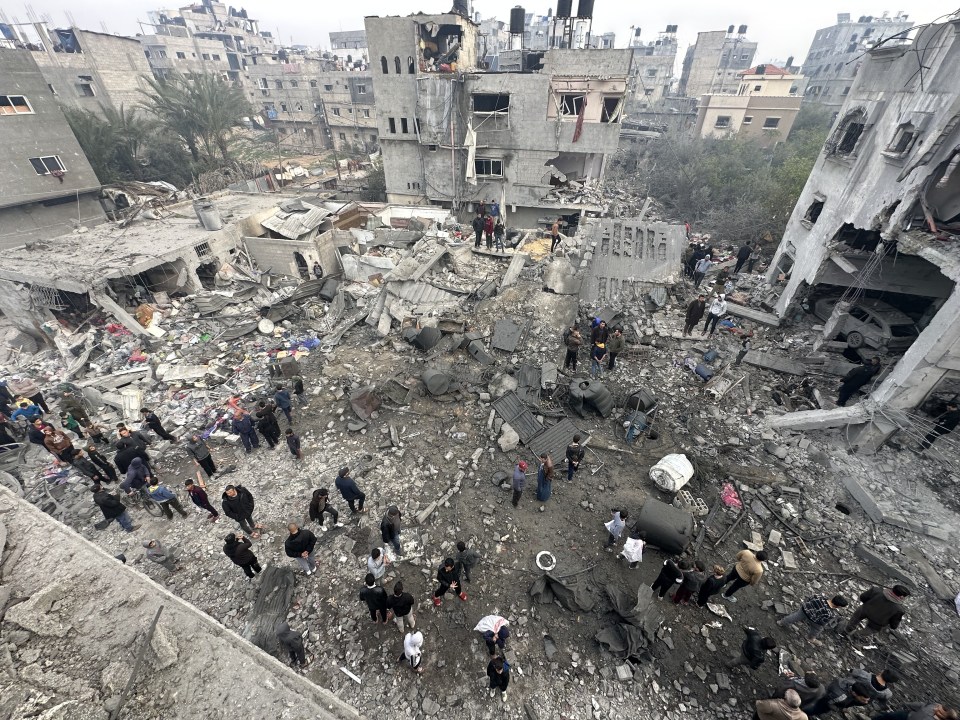 Aerial view of bomb damage and people surveying the destruction.