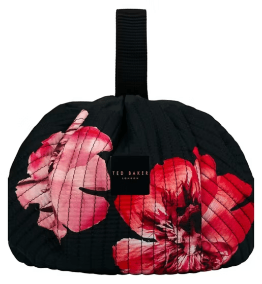 Black quilted bag with pink and red floral print and a black handle.