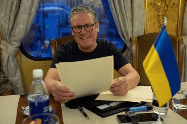 Man reviewing documents at a table with a Ukrainian flag in the background.