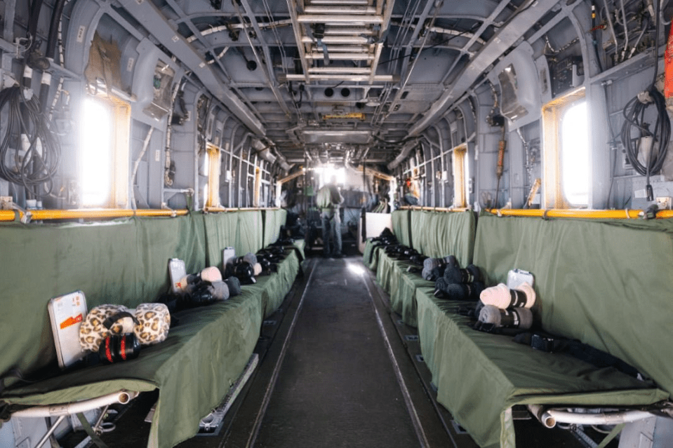 Interior of a military transport aircraft with equipment and blankets on the seats.