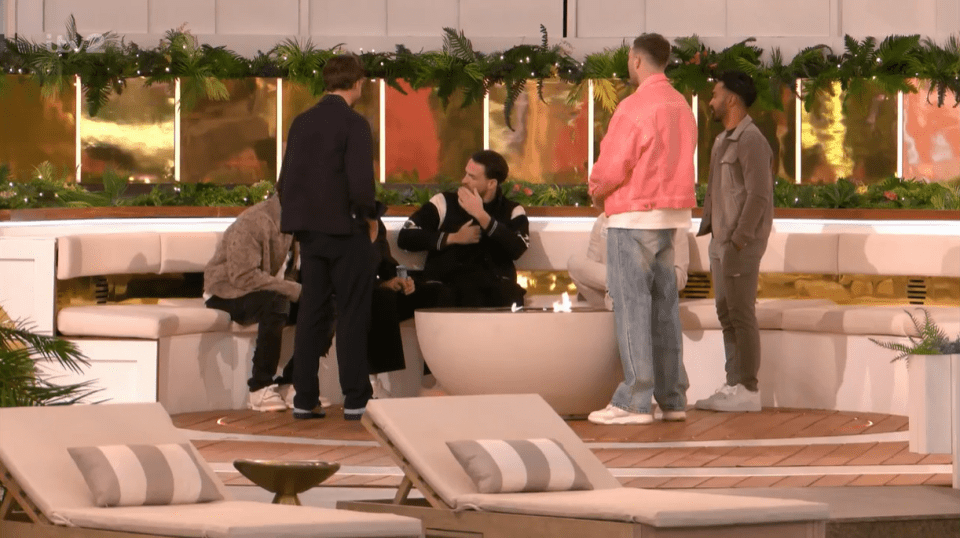 Group of men talking around a fire pit.