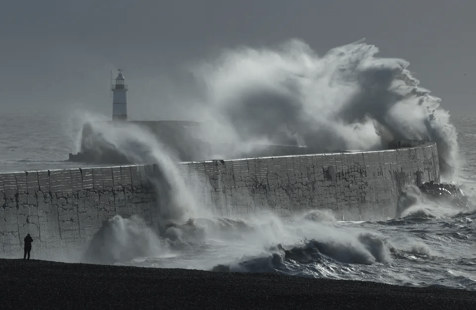 Waves crashing against a seawall and lighthouse.