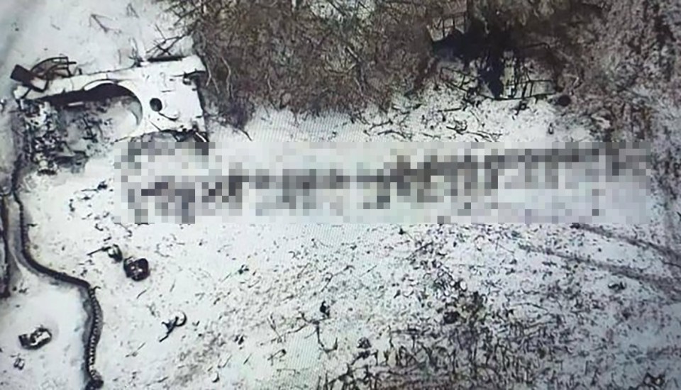 Destroyed military vehicle in snowy landscape.