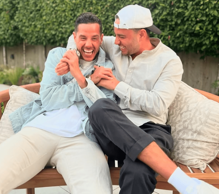 Two men laughing and playfully holding each other on a bench.