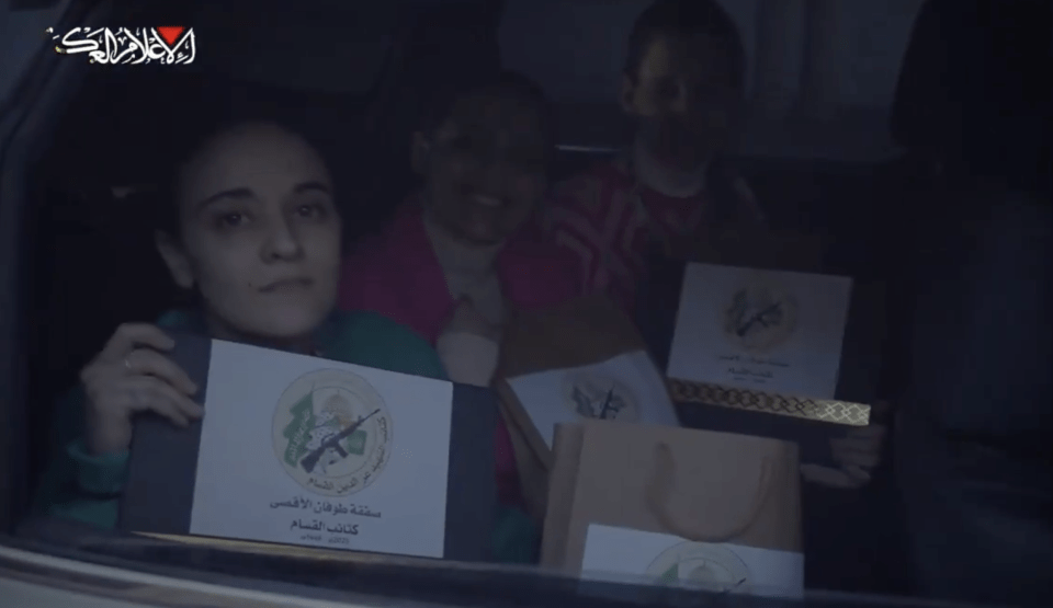 Women in a car holding certificates with a military emblem.