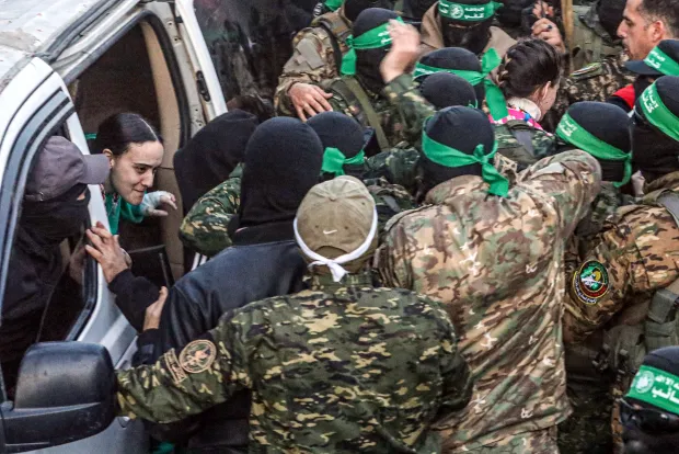 A woman being pulled from a vehicle by armed fighters.