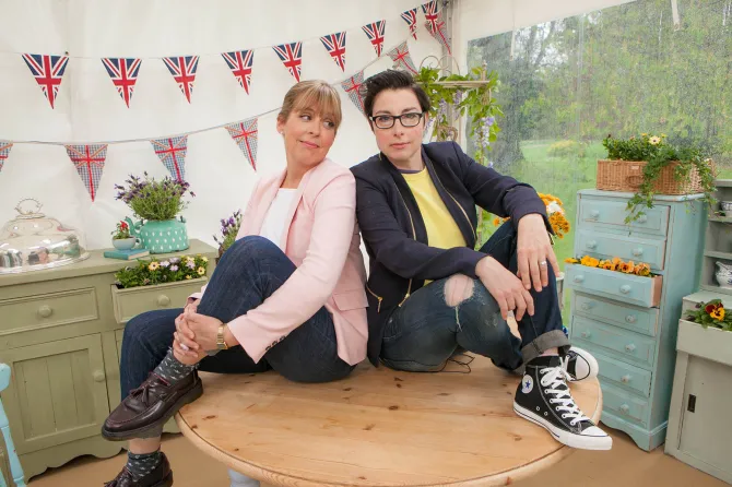 Two women sitting on a table in a garden setting.