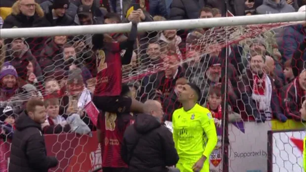 Soccer player celebrating a goal by climbing over the net.