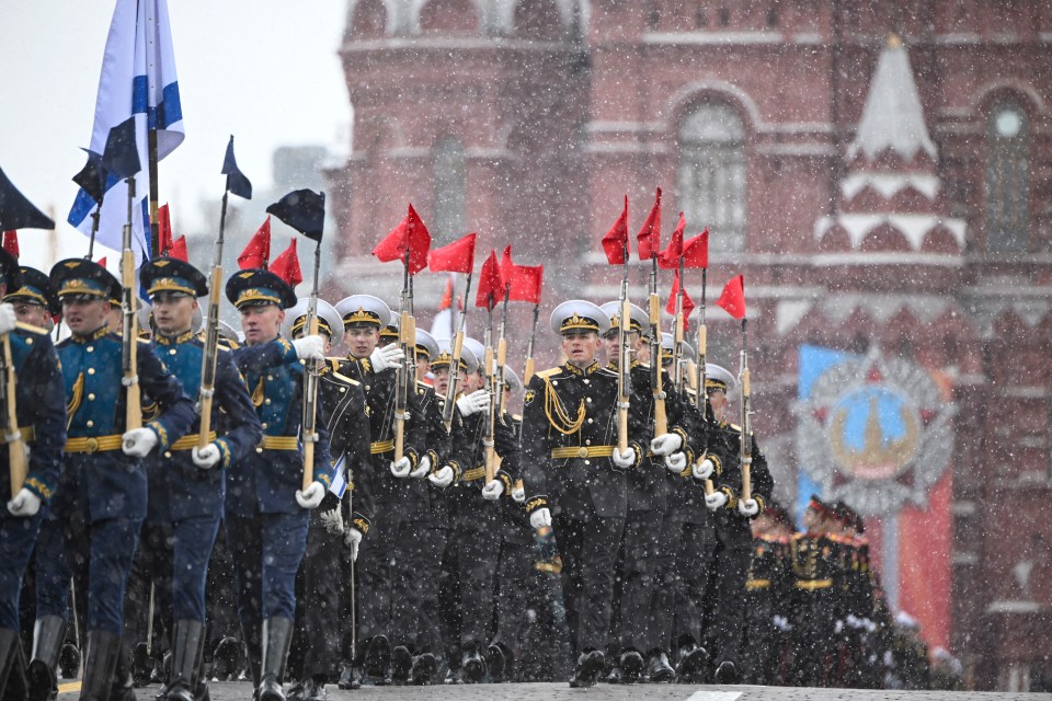 Military personnel in uniform marching in the snow.