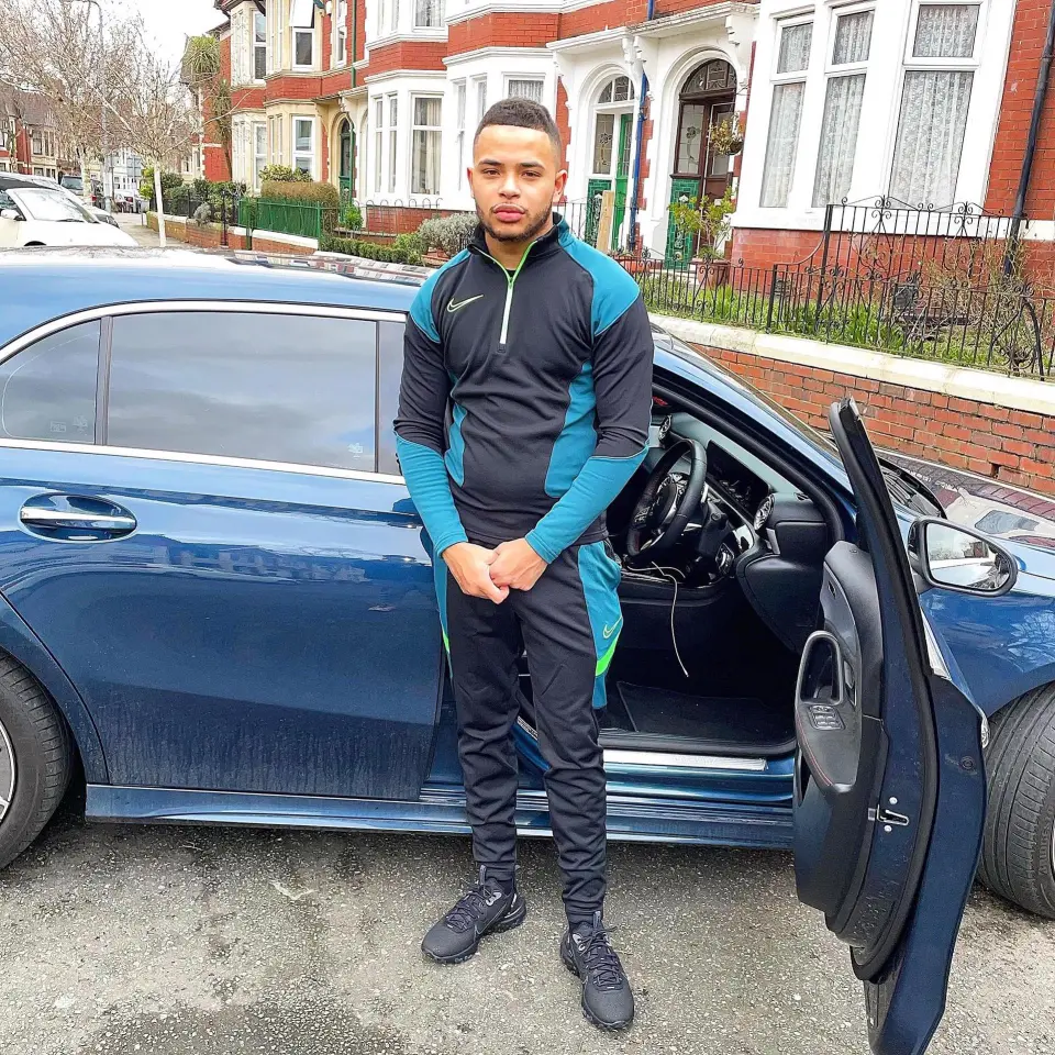 Man in Nike tracksuit standing next to a car.