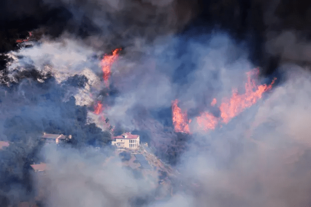 Wildfire engulfing a hillside with houses.