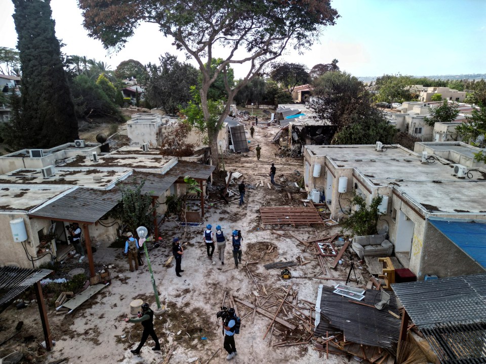 Aerial view of damaged buildings and debris, with people surveying the scene.