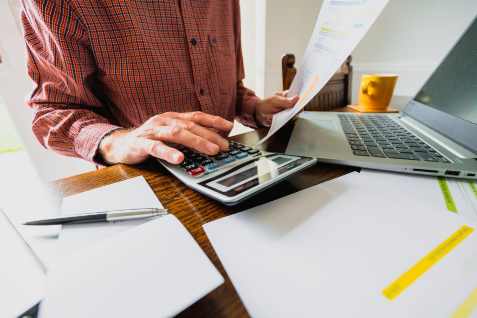 Senior man reviewing bills and using a calculator.