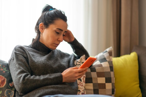 Woman sitting on a sofa looking at her phone.