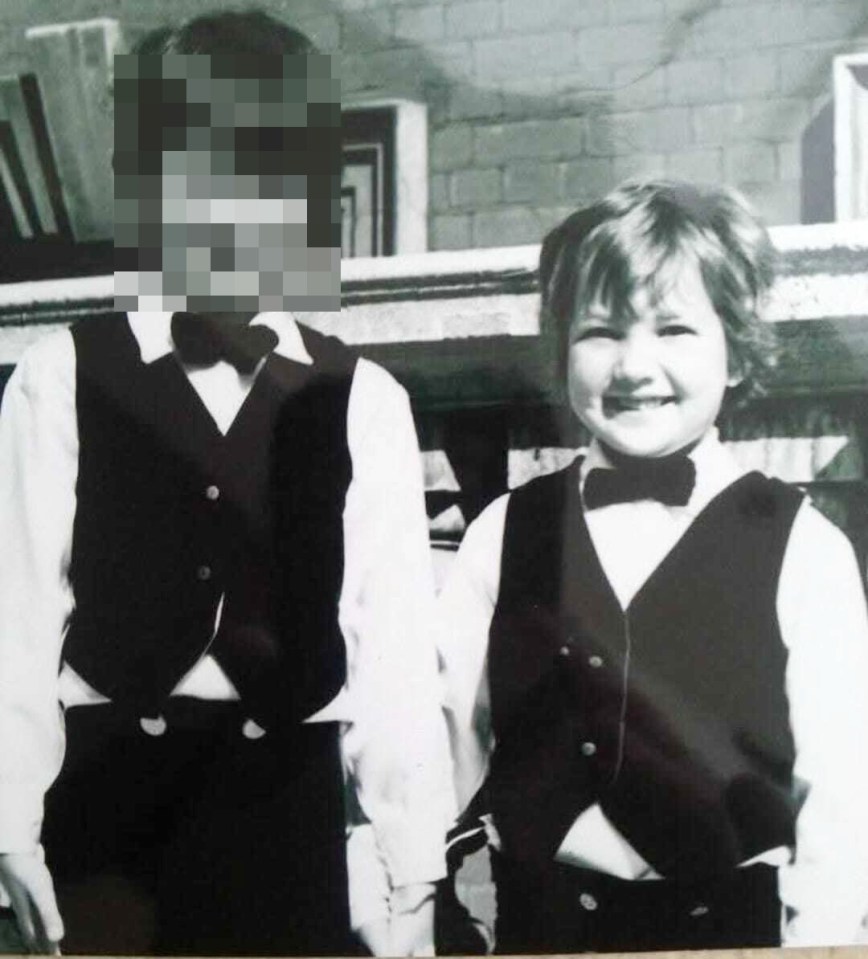 Black and white photo of two young boys in vests and bow ties.  One boy's face is blurred.