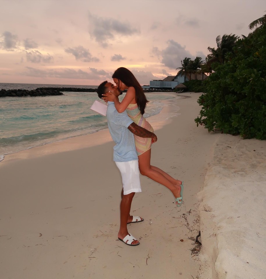 Couple kissing on a beach at sunset.