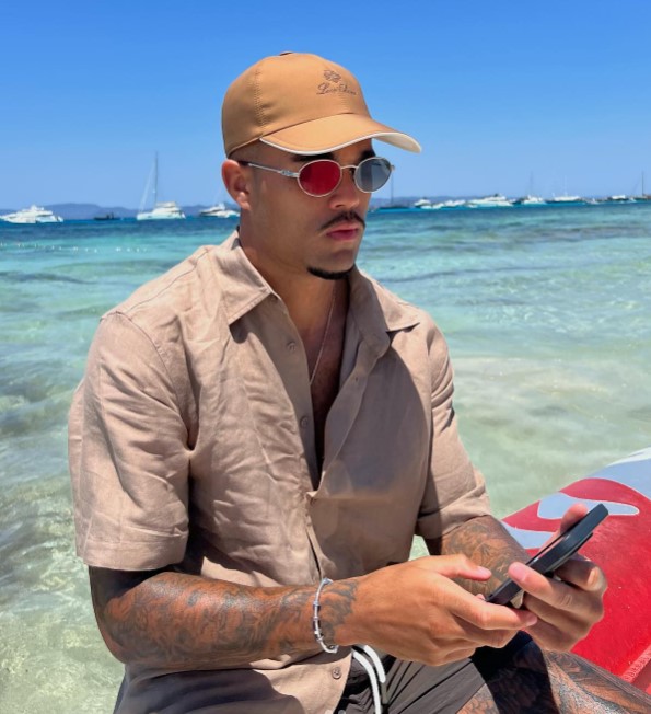 Justin Kluivert looking at his phone on a beach.