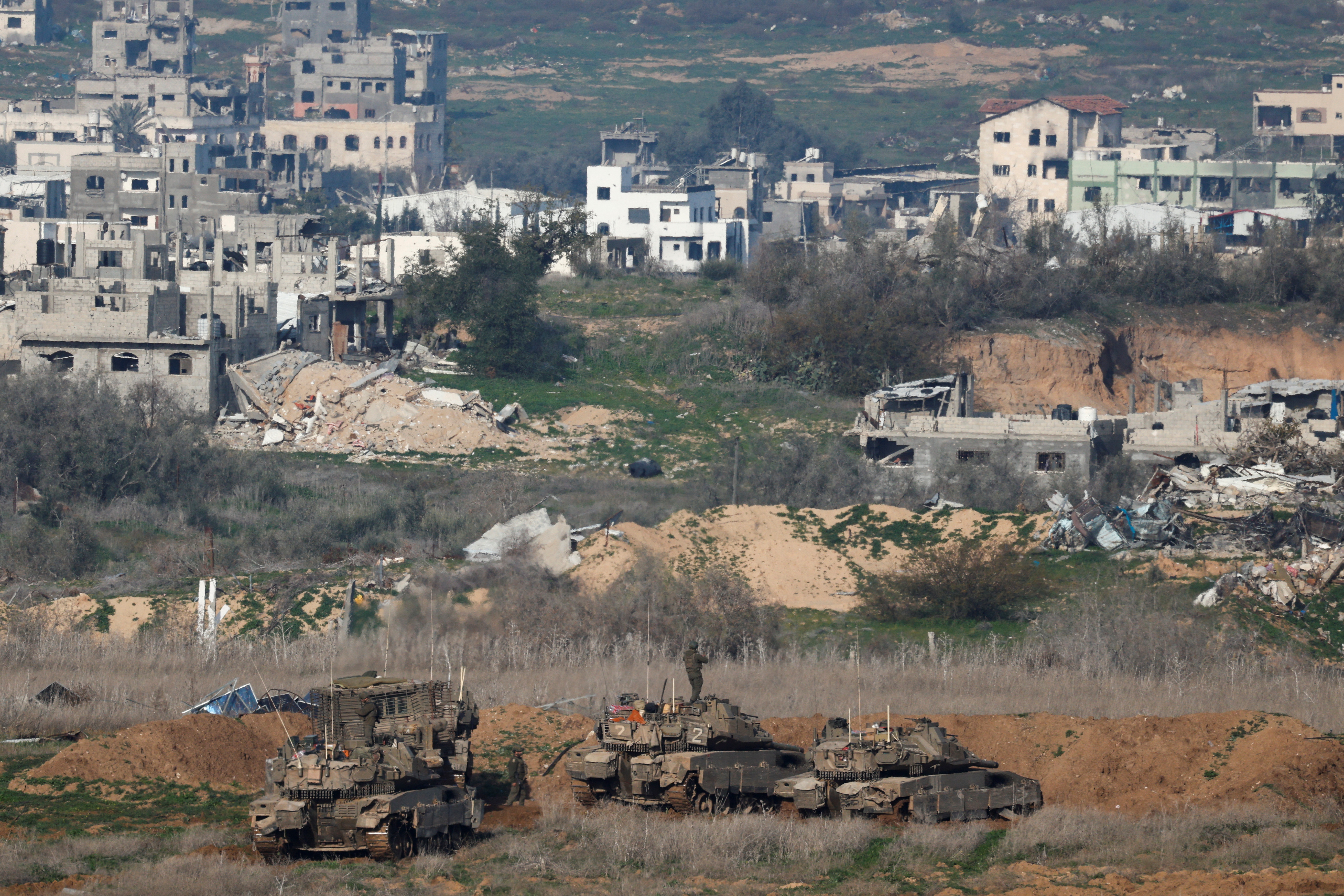 Israeli military vehicles positioned in the Gaza Strip near damaged buildings.