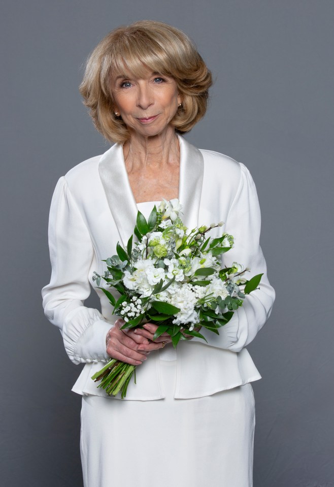 Gail Rodwell, Coronation Street character, in a white wedding outfit, holding a bouquet.