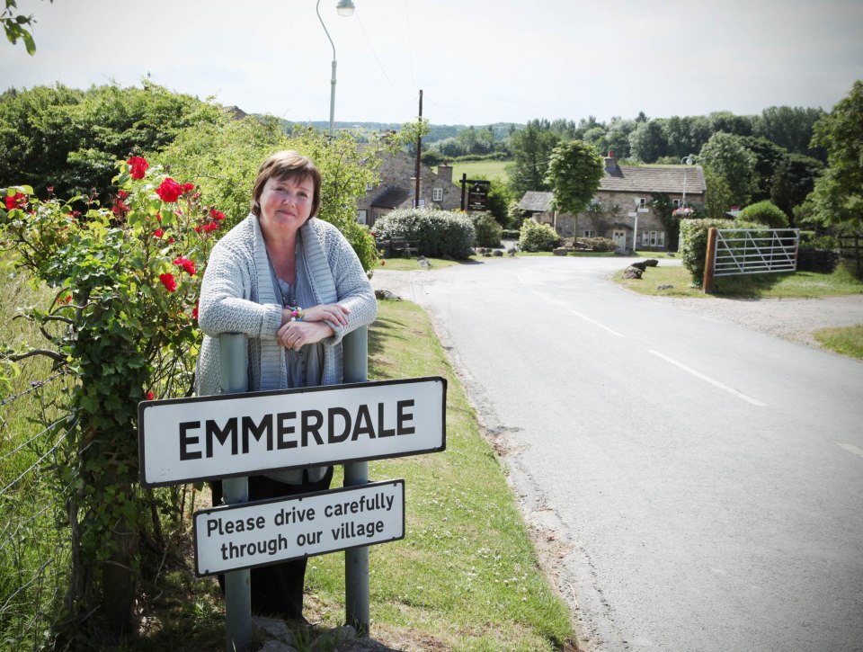 Pauline Quirke by an Emmerdale village sign.