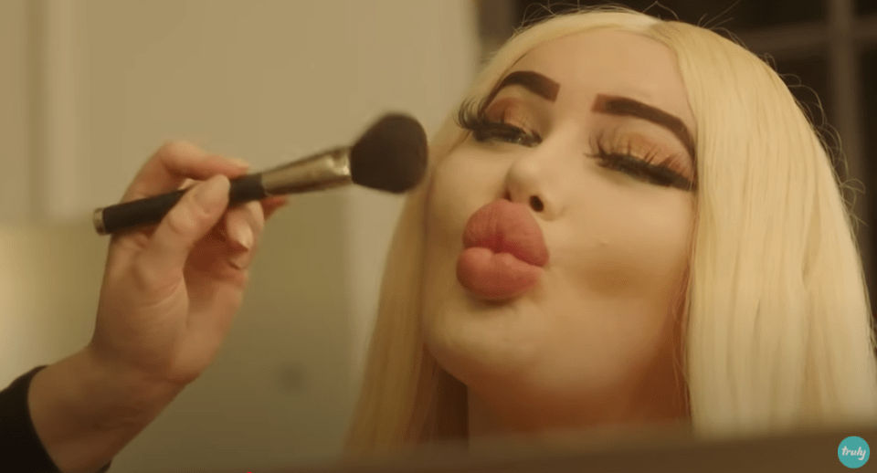 Woman with blonde hair having makeup applied to her face.