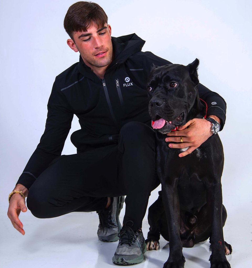 Jack Fincham crouching with his black Cane Corso dog, Elvis.