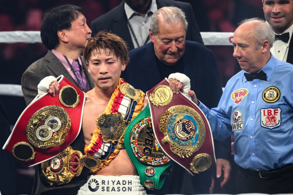 Naoya Inoue holding multiple boxing championship belts.