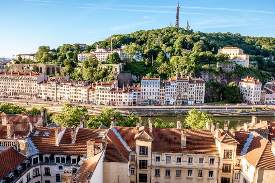 Aerial view of Lyon, France, showing buildings, a river, and Fourvière Hill.