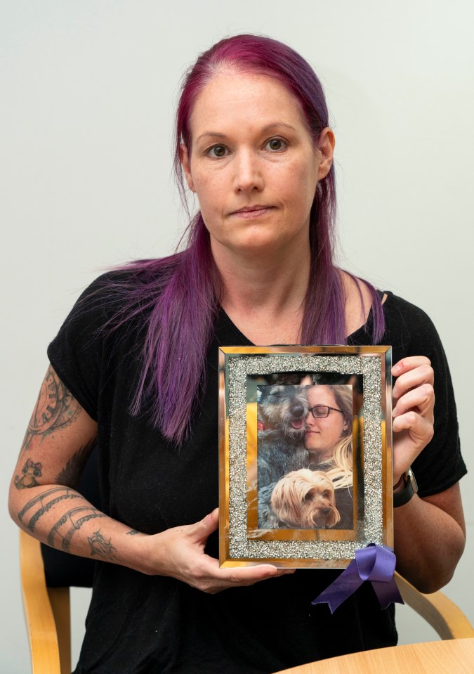 A woman holds a framed photo of herself and two dogs; she is the stepmother of Jodie Chesney, who was murdered.