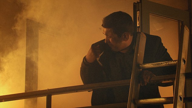 Man in a smoky room, leaning on a ladder.