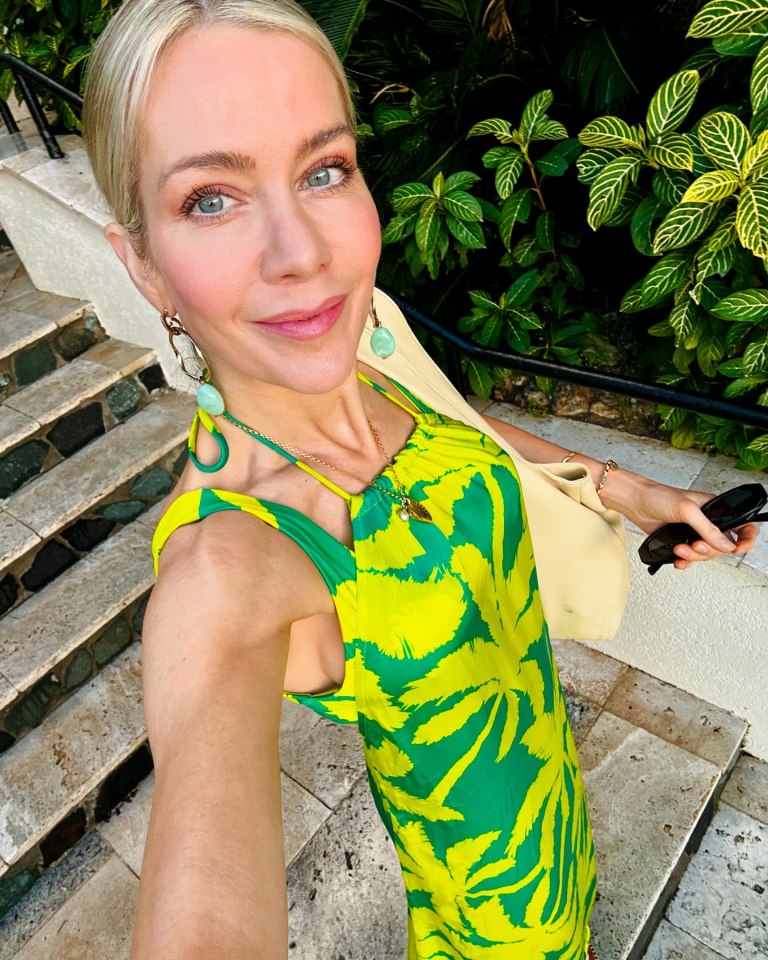 Woman in green and yellow dress on stone steps.