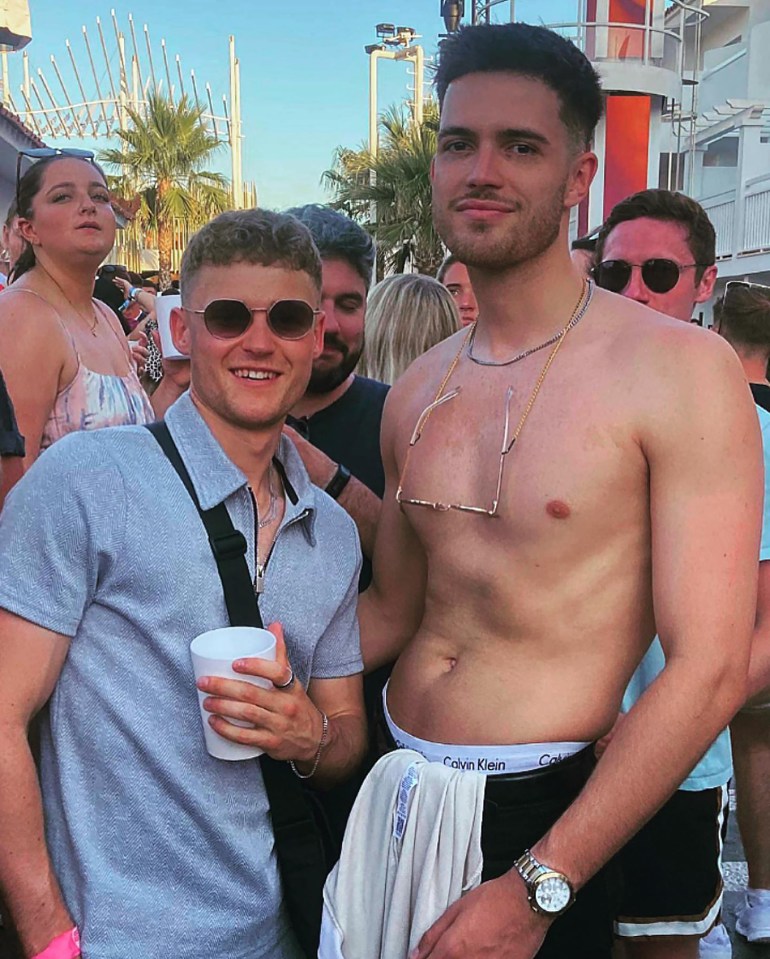 Two men posing for a photo, one shirtless and the other wearing a gray shirt.