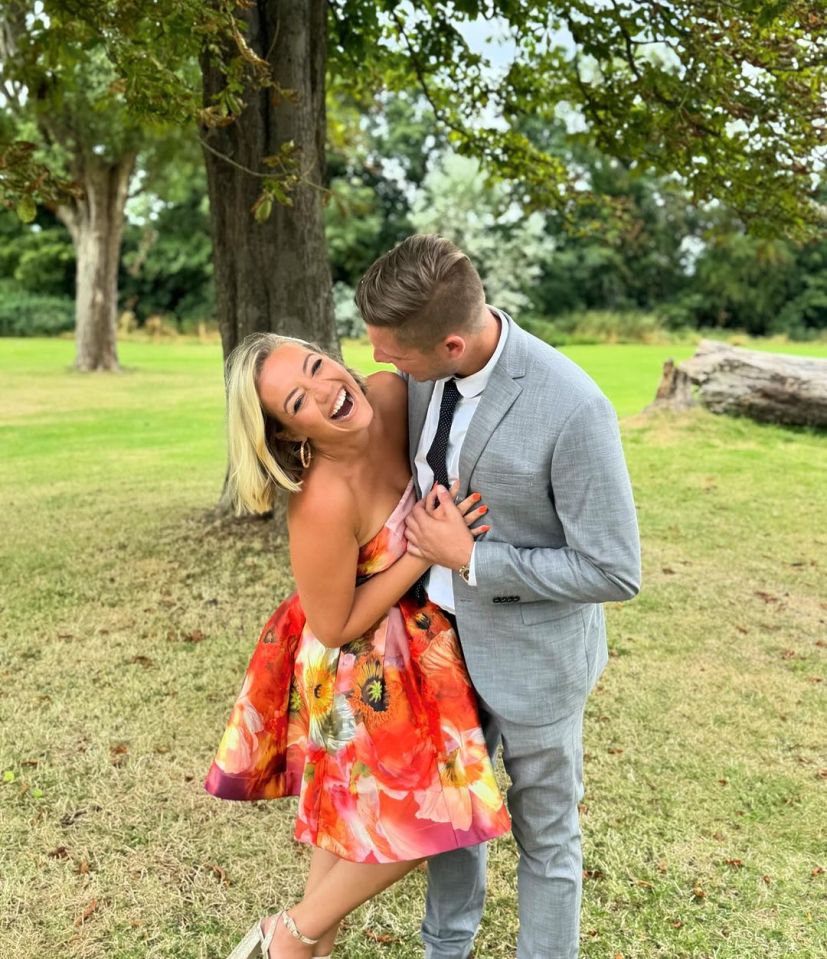 Woman in floral dress laughing with man in gray suit.