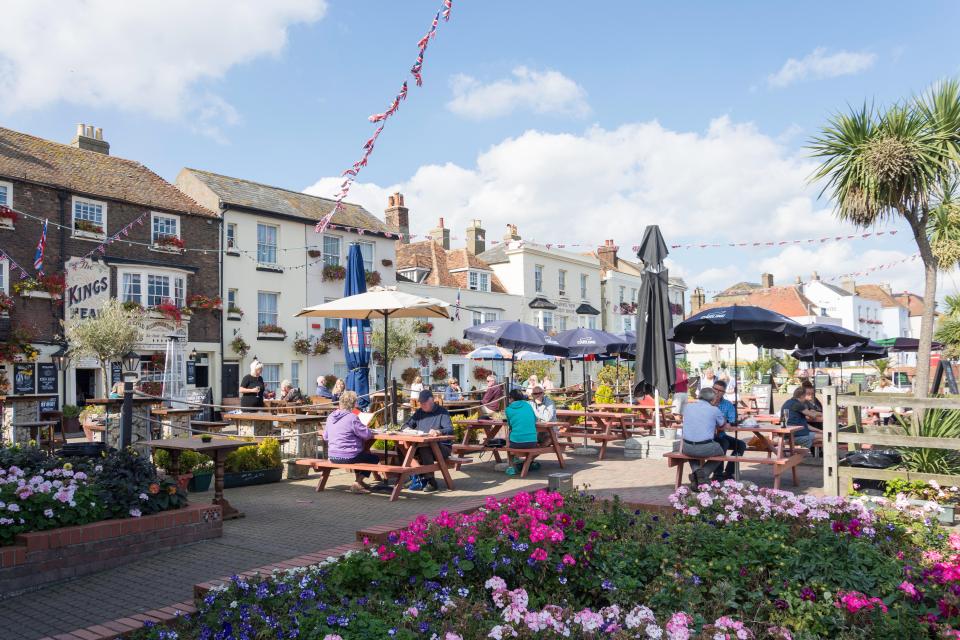 Patrons seated at outdoor tables in front of pubs and shops.