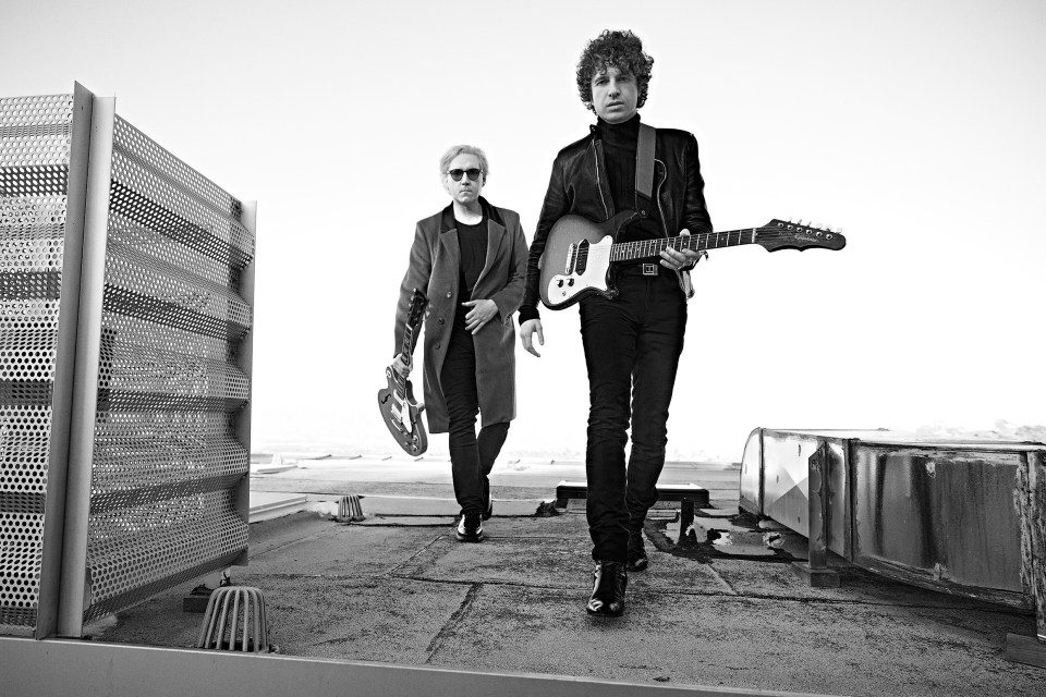 Black and white photo of The Kooks band members walking on a rooftop.