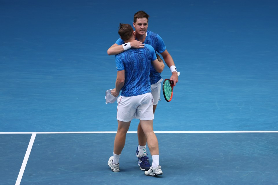 Two tennis players embracing after winning a doubles match.