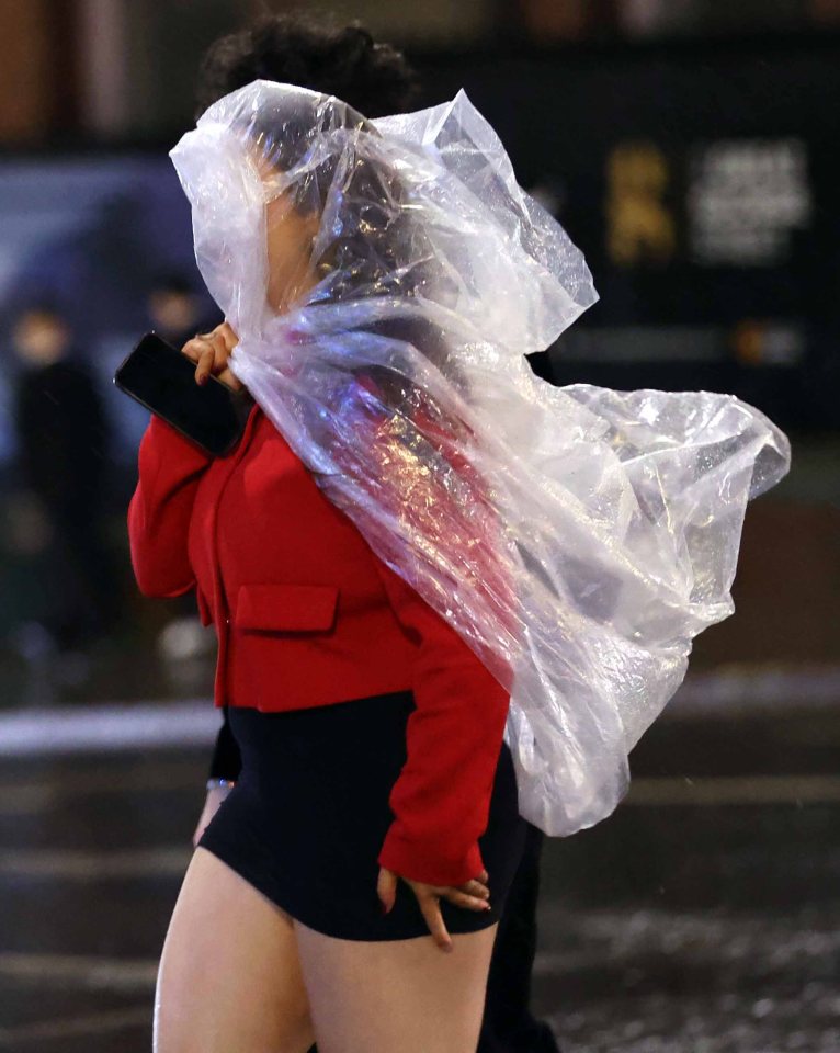 A woman uses a plastic bag as a makeshift defence