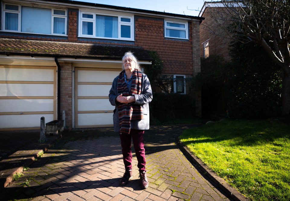 An elderly woman stands outside her house, which is slated for demolition to make way for a third runway at Heathrow Airport.